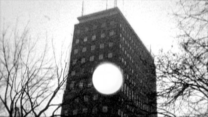 film still: The cold moon penetrates the prefabricated office block then envelopes it in night

